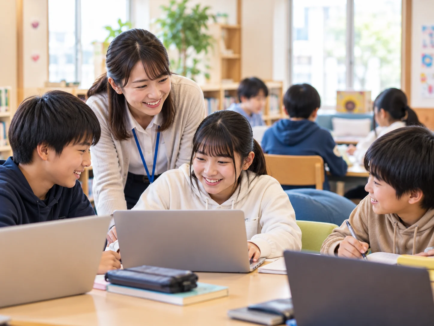 学習支援施設のような教室で先生と子どもたちがパソコンを囲み、一緒に学ぶ様子