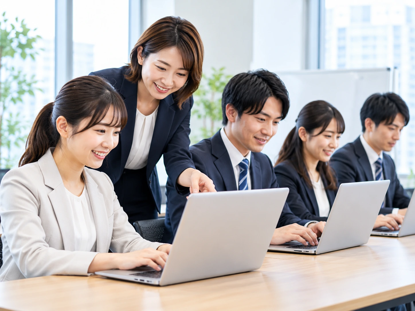 オフィスでノートパソコンを使い研修を受ける社会人のグループ