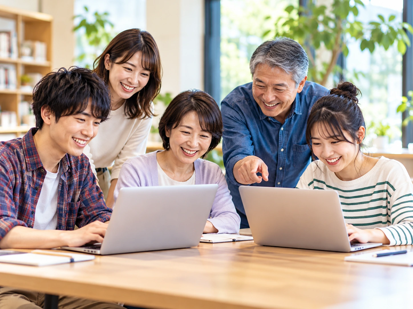 さまざまな年代のメンバーが一緒にノートパソコンを使って学ぶ様子